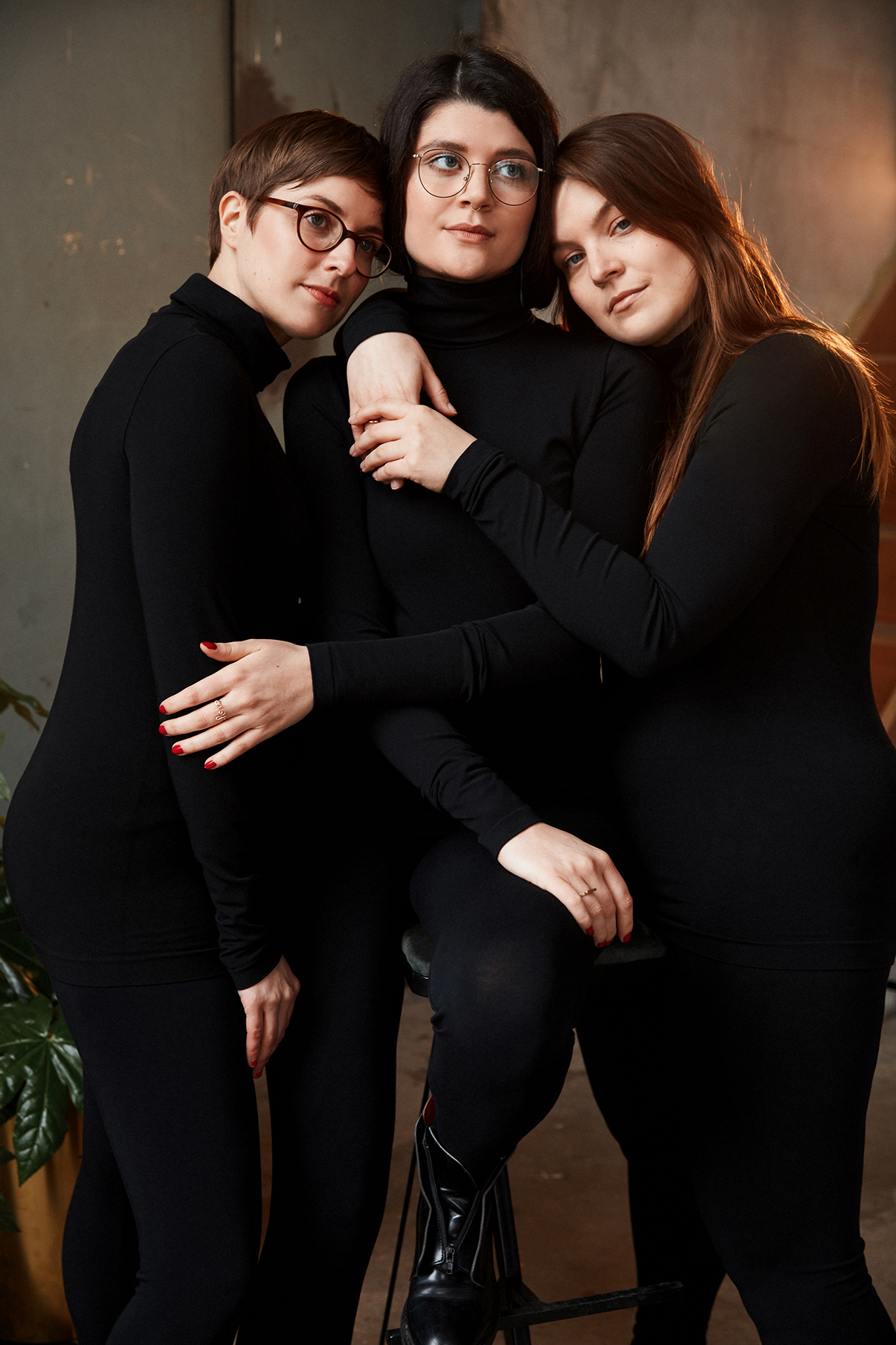 3 Frauen tragen schwarze Leggins und Rollkragenpullover von Wolford und stehen eng umeinandergeschlungen zusammen