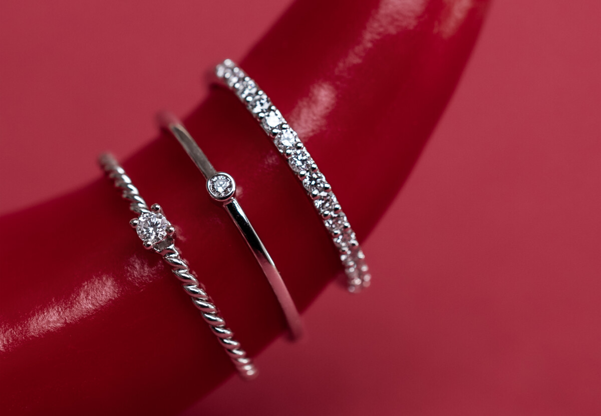 fejn: drei mit Diamanten besetzte Silberringe auf einem leuchtend roten Hintergrund