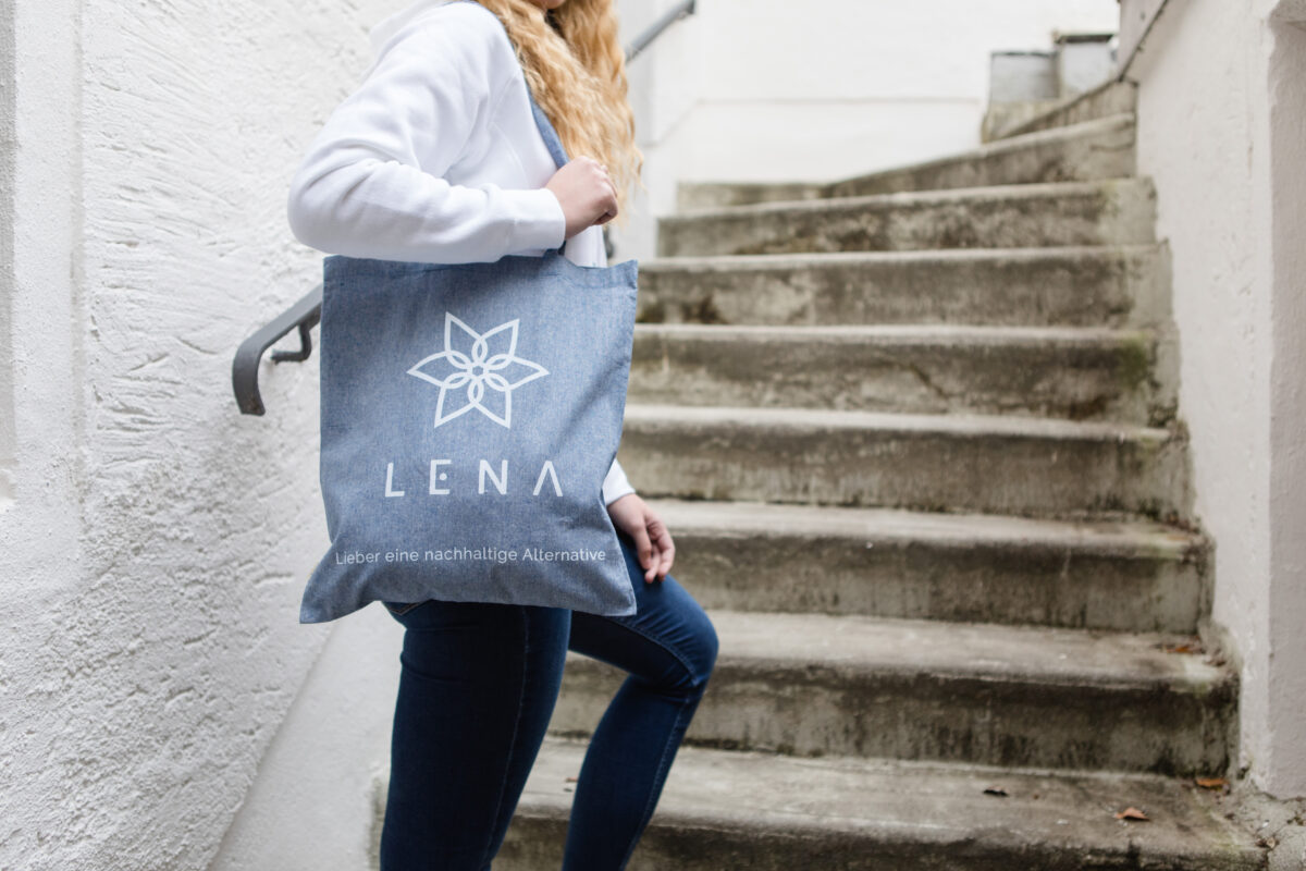LENA Shop, eine Frau in Jeans und Sweatshirt trägt eine blaue Tasche von LENA, Accessoires