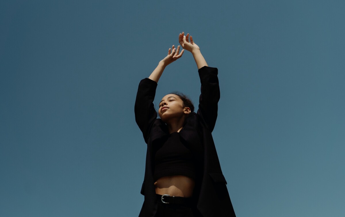 Person streckt Hände zum blauen Himmel