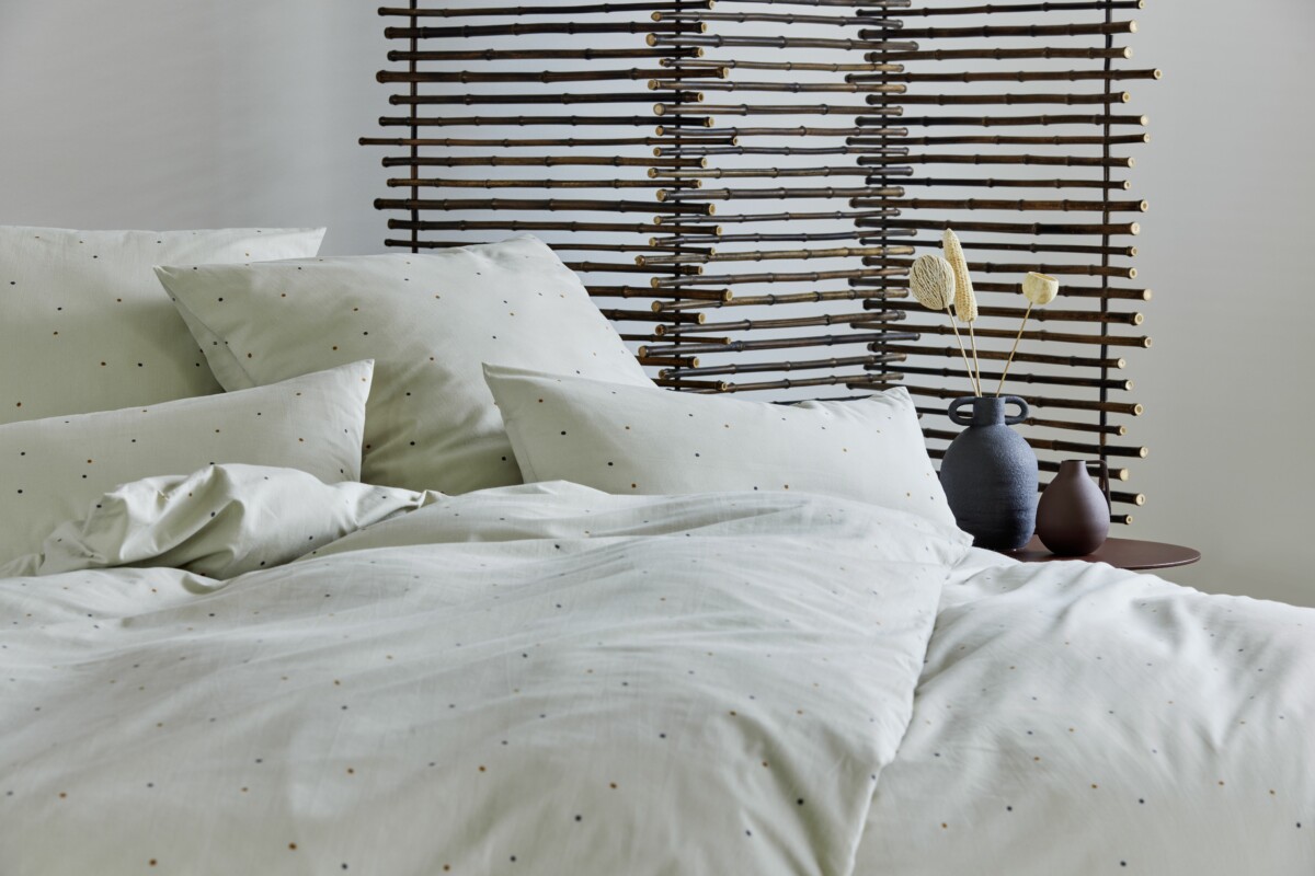 Lama Living, ein Bett mit drapierten Kissen und Decken, Interior