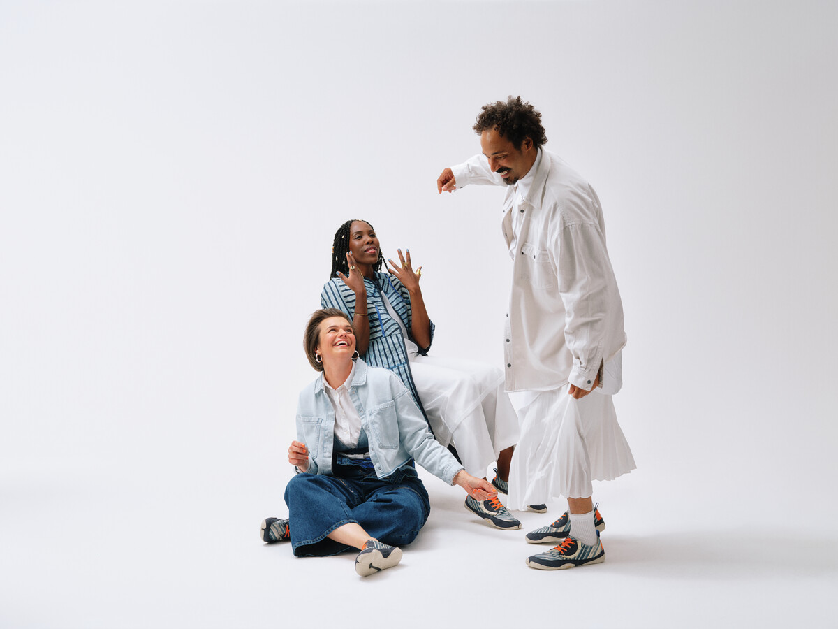 3 lachende Menschen vor weißem Hintergrund. Der Schuh ONU will eine neue Sichtweise auf African Fashion bieten.
