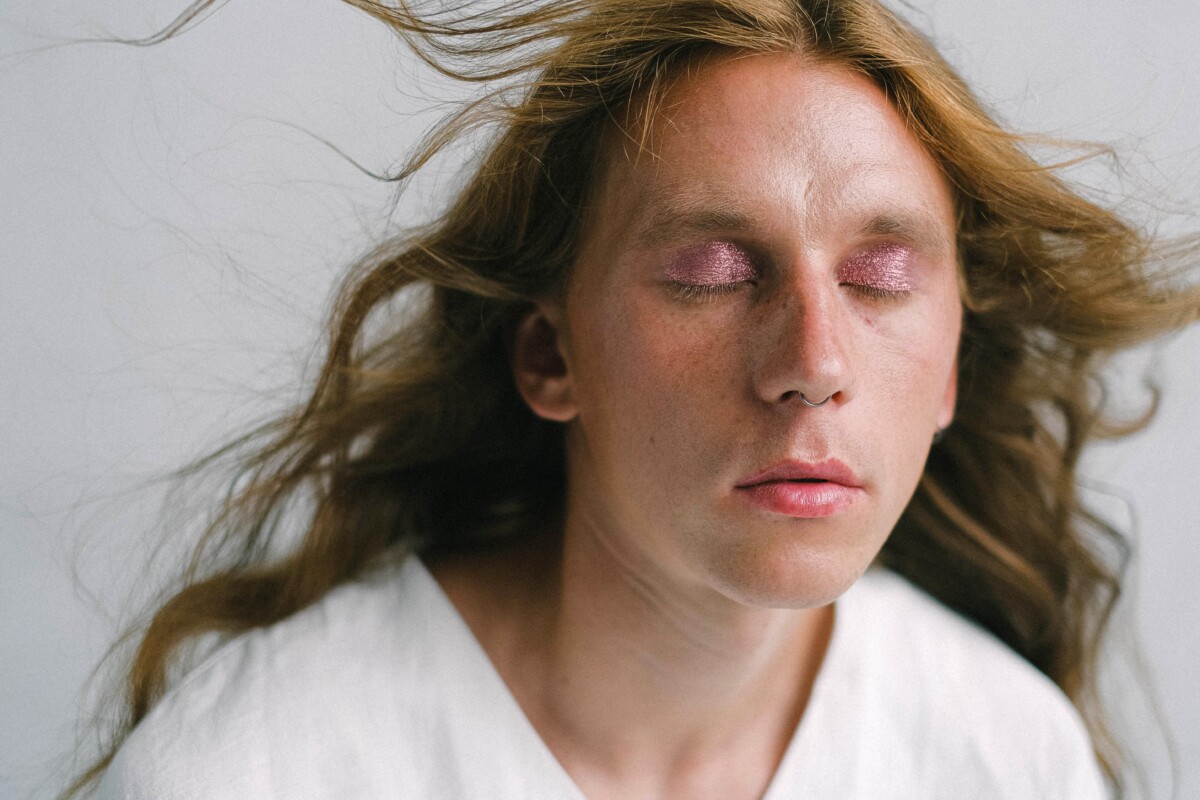 Titelbild Mensch im weißen Oberteil mit langen Haaren und geschlossenen Augen zum Thema Branchentrends nachhaltige Mode